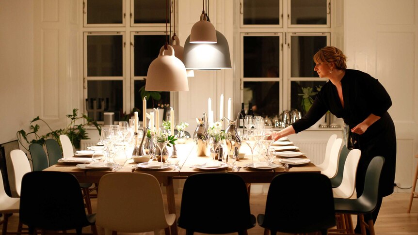 A woman sets the table for Christmas dinner.