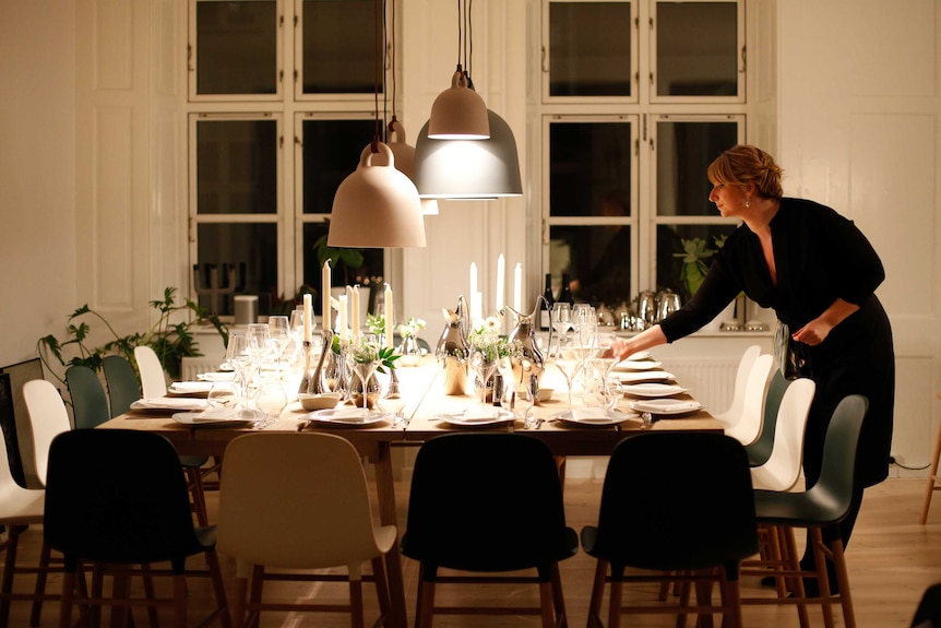 A woman sets the table for Christmas dinner.