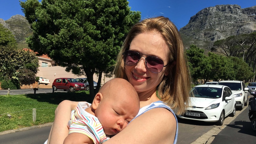 A women in her thirties holding a sleeping baby