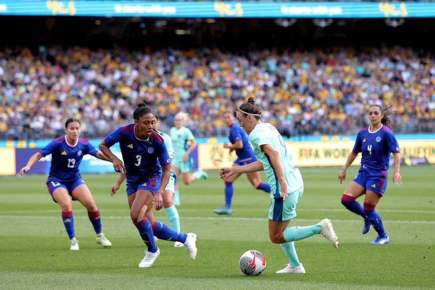 Philippines player Jessika Cowart is tracking back in defence, as Matildas player Caitlin Foord dribbles.