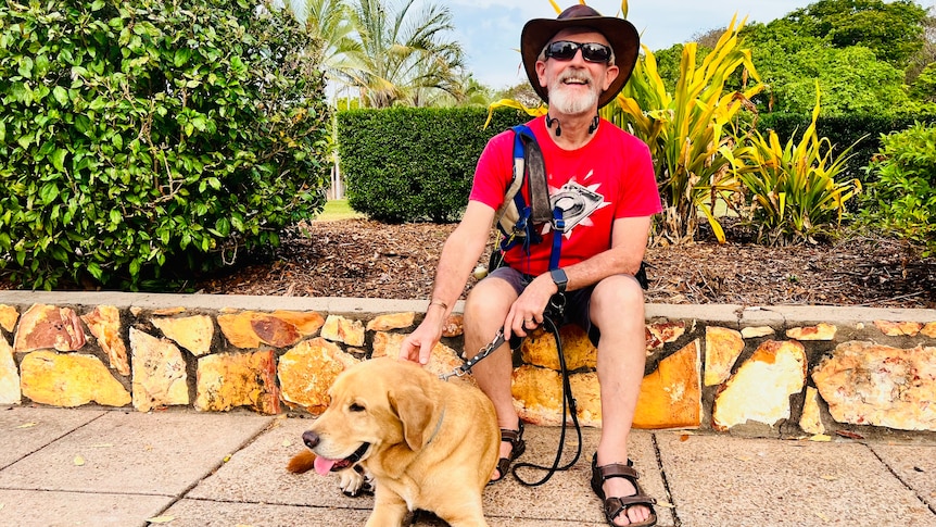 man sits on ledge outside with seeing eye dog