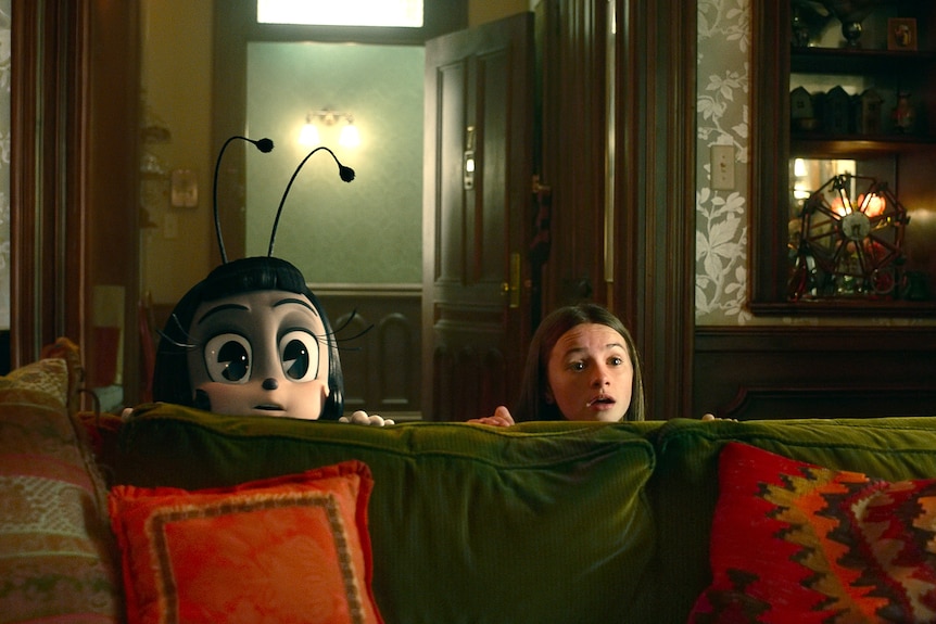 An animated bug and a young girl peer over the top of a couch, looking shocked
