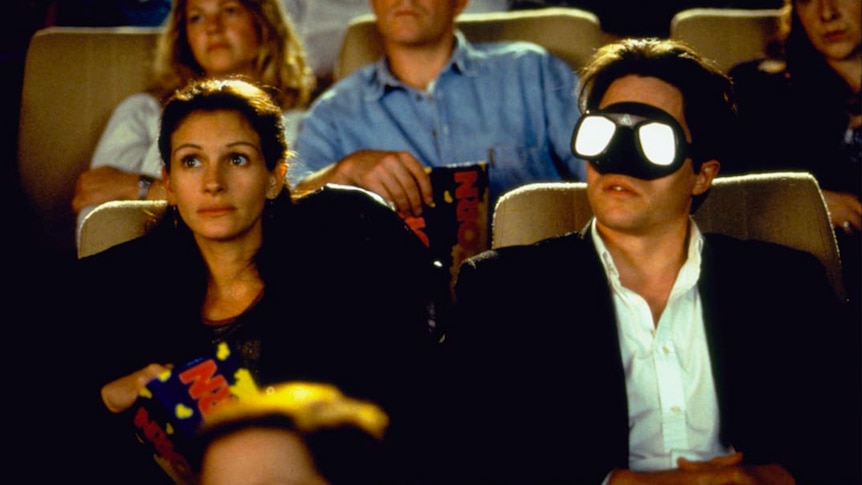 Julia Roberts watches a film with Hugh Grant at the cinema. Grant wears diving goggles.