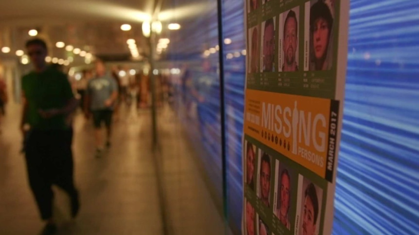 Missing persons poster on a railway tunnel wall with blurry people walking past