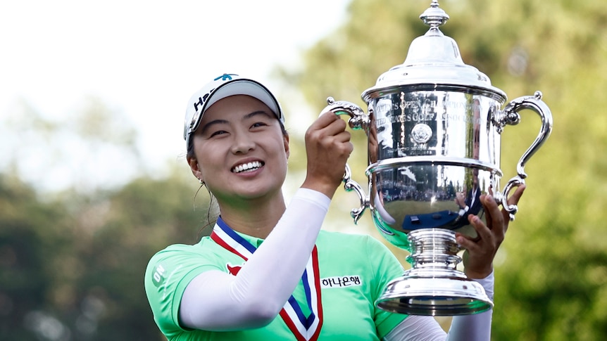 A smiling Minjee Lee wears a medal around her neck as she lifts up a silver cup after winning the US Women's Open.  