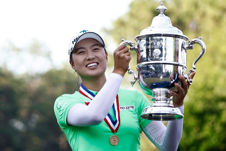 A smiling Minjee Lee wears a medal around her neck as she lifts up a silver cup after winning the US Women's Open.  