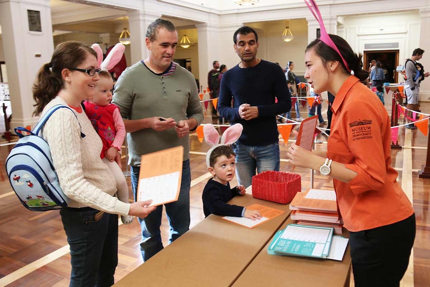 A woman hands a family Great Easter Egg Trail maps and clues.