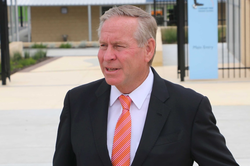 A mid shot of Colin Barnett in front of a building wearing a suit and tie.