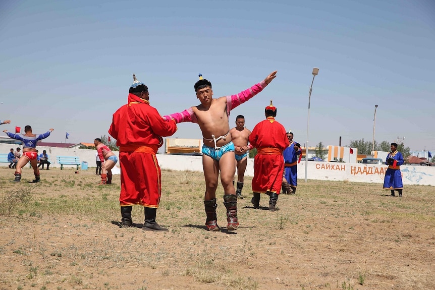 Mongolian wrestlers raise their arms in a ceremony dance before competing.