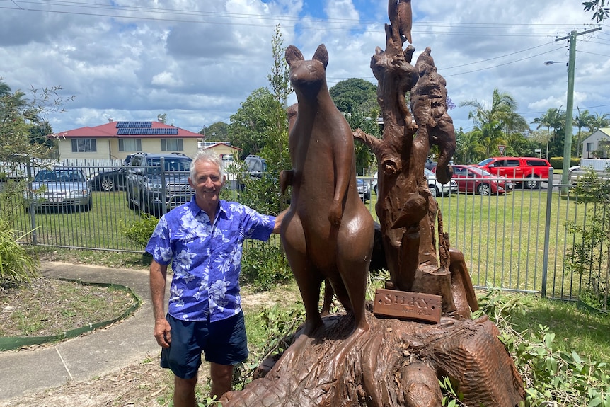 Middle aged man  standing next to chainsaw sculpture