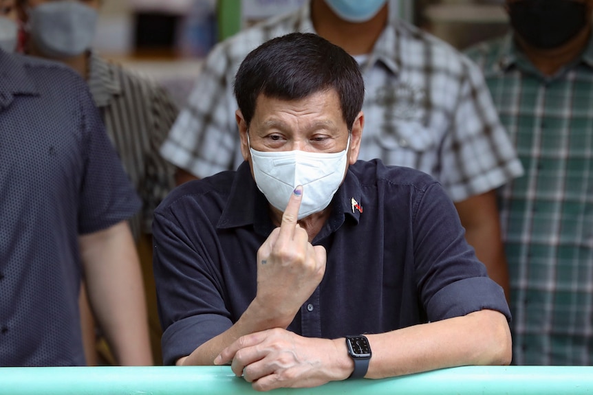 Philippine President Rodrigo Duterte shows ink on his finger to mark that he has finished voting