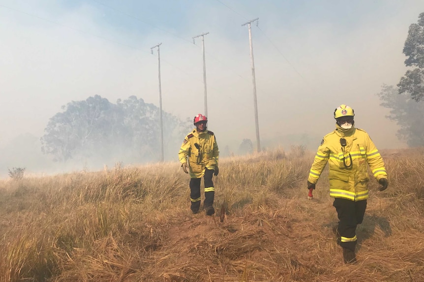 Firefighters walked through long grass on a property shrouded in smoke.