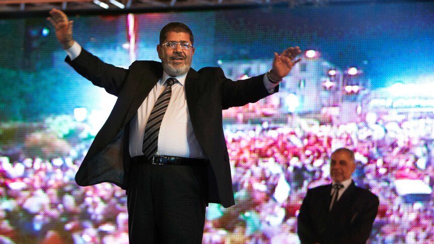 Muslim Brotherhood's presidential candidate Mohammed Morsi holds a rally in Cairo, holds his hands in the air in front of screen