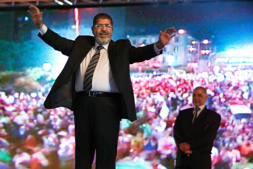 Muslim Brotherhood's presidential candidate Mohammed Morsi holds a rally in Cairo, holds his hands in the air in front of screen