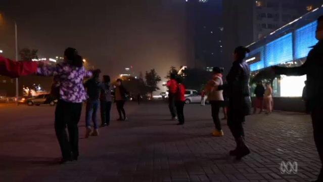 A group of people dance in Beijing street at night
