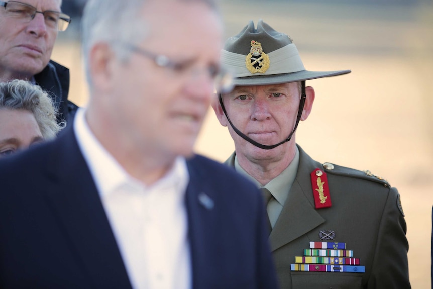 Stephen Day stands behind Scott Morrison at a press conference in a drought area