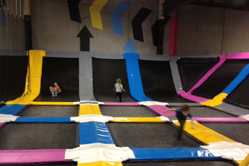 Children play at an indoor trampoline centre.