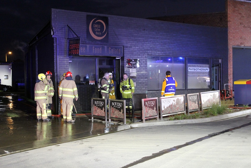 Firefighters stand outside the Circle Coffee House in New Norfolk.