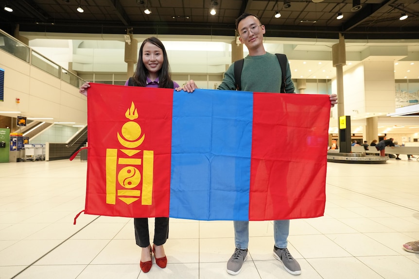 L'homme et la femme brandissent le drapeau mongol à l'aéroport.