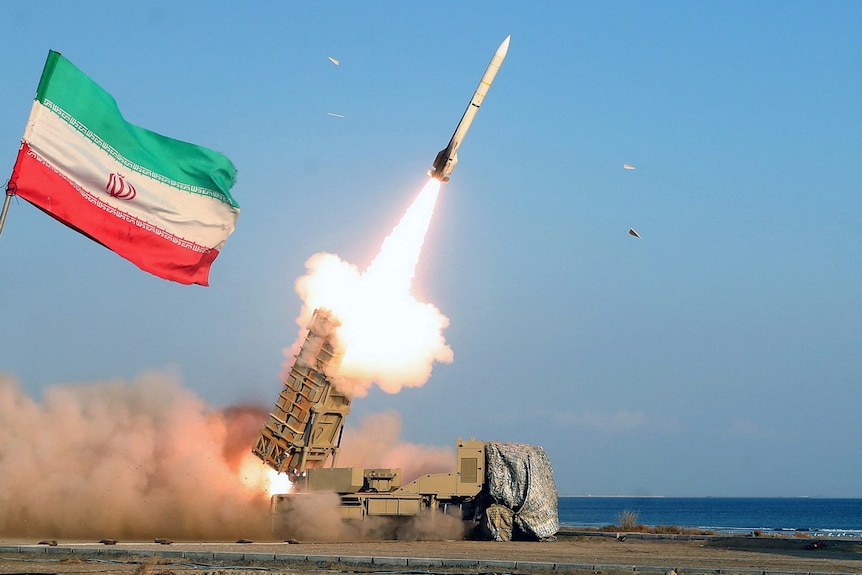Iranian flag waving in the sky as a missile nearby is launched.