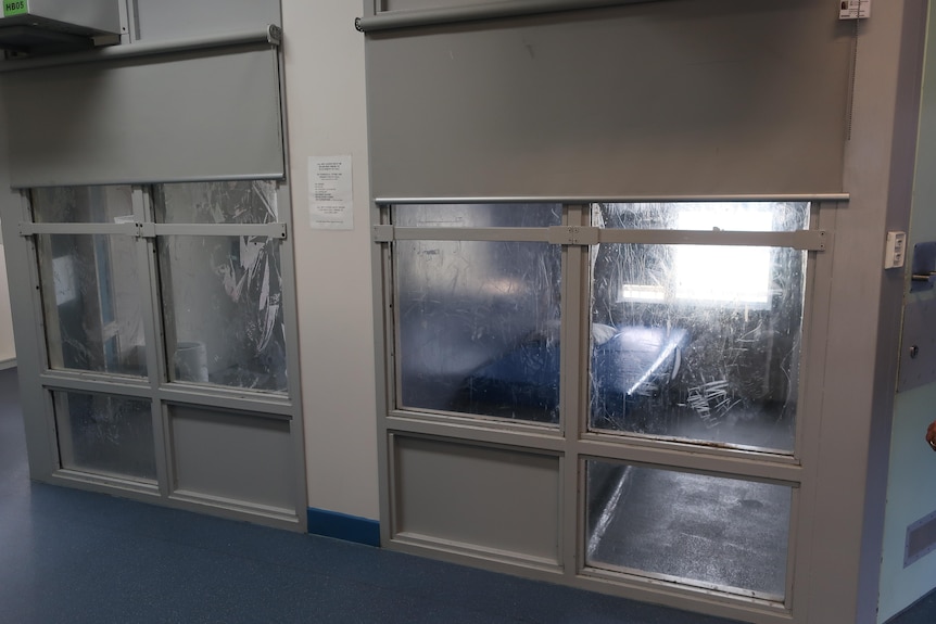 Detention cells with scratched windows.