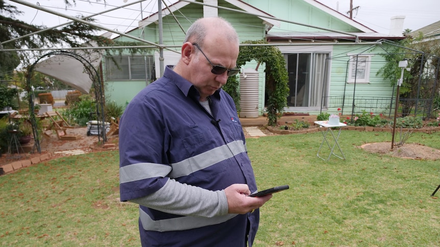 A man on his phone in a yard.
