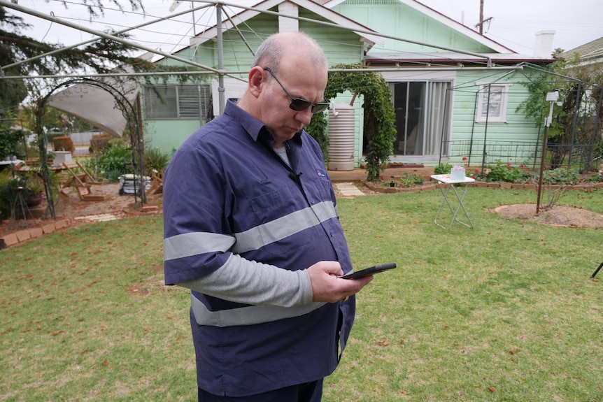 A man on his phone in a yard.