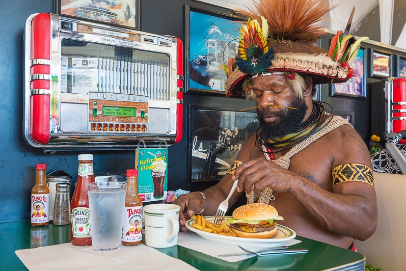 The Huli chief eating a burger in a coffee shop in San Francisco.