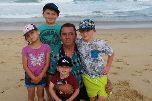 A man on the beach with four kids