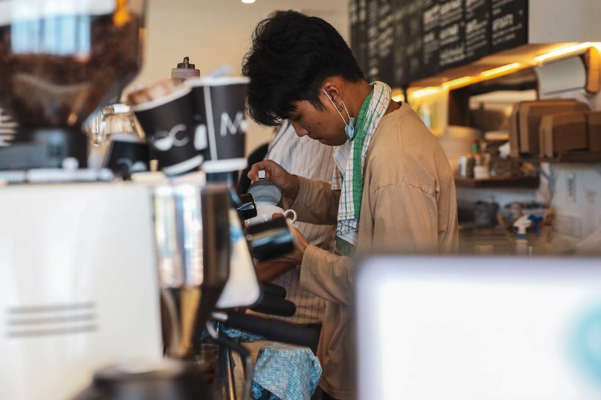 A man makes coffee in a cafe