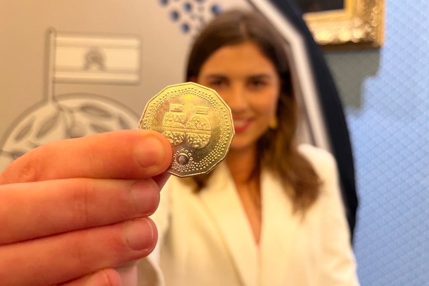 A woman holds up a specially designed 50 cent coin