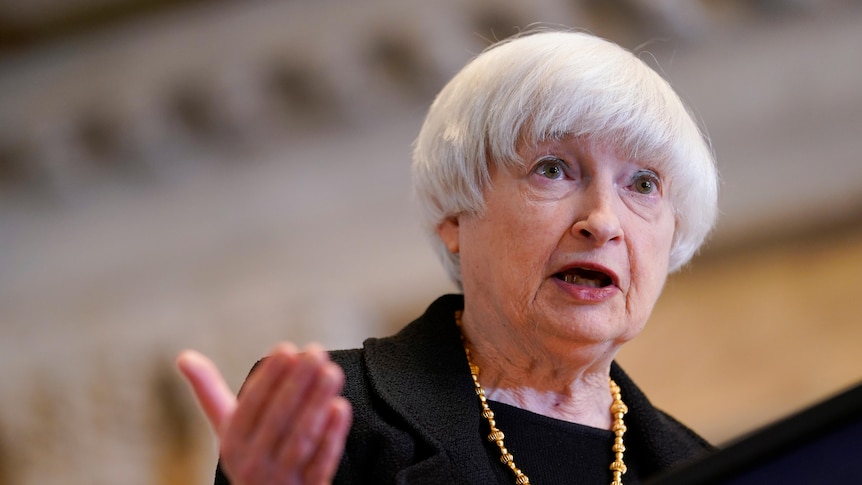 A woman gestures while speaking at a lectern 