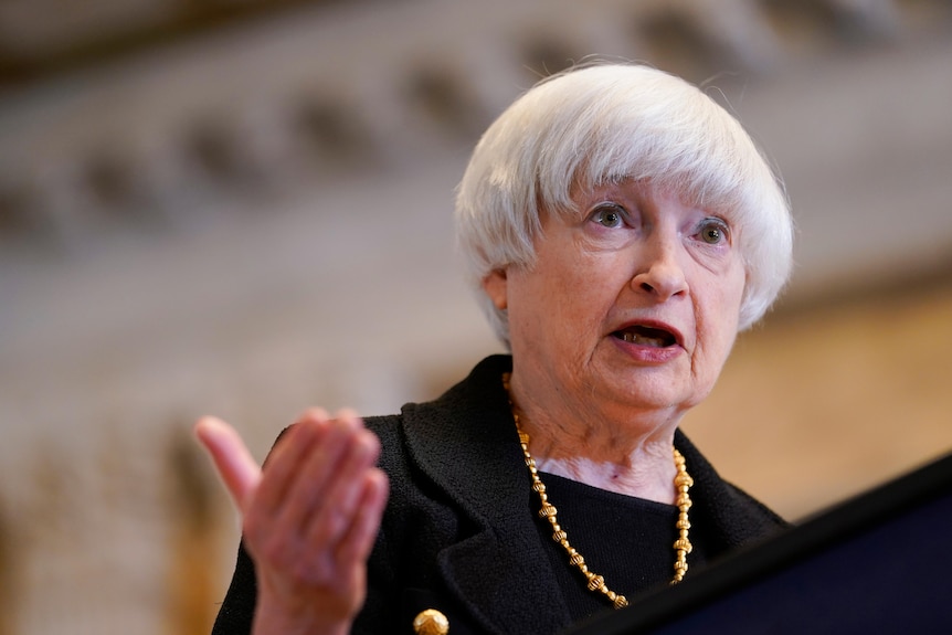 A woman gestures while speaking at a lectern 