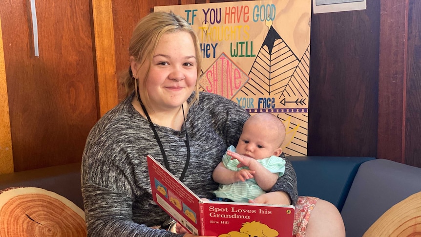 A young mother reads a book to her baby