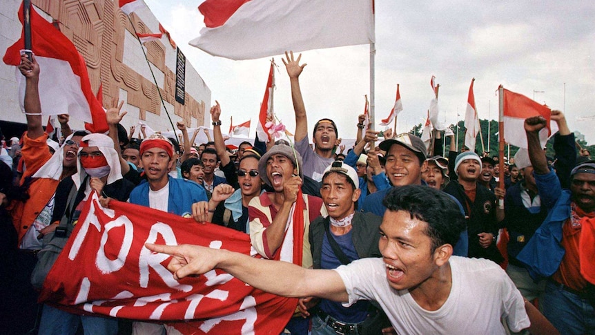 Indonesian students wave flags after hearing about Suharto's resignation. They are cheering.