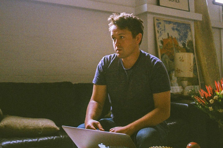 A man sitting on a couch with a laptop computer in front of him on a low table