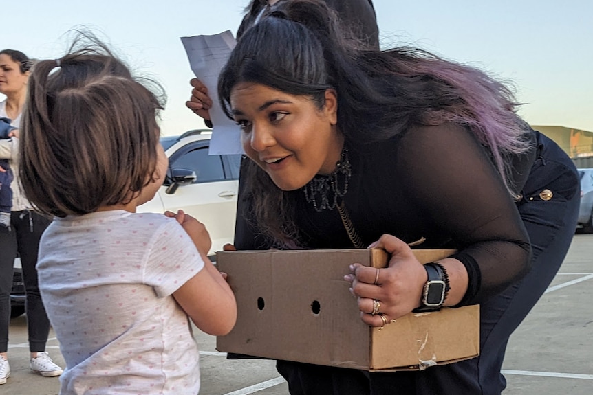 Atena Kashani with a young girl while holding a box of doves at Masjid Nabi Akram mosque in Shepparton.
