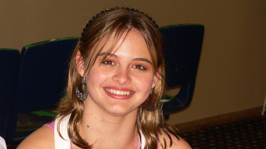 A young girl smiles at the camera.