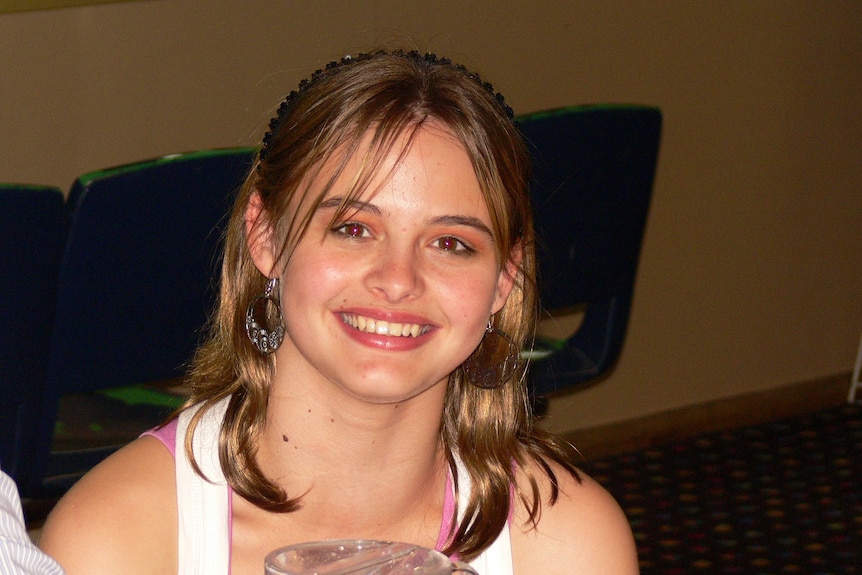 A young girl smiles at the camera.