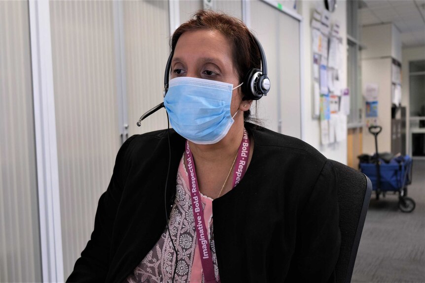 Joy sits at a desk wearing a blue mask and headset.