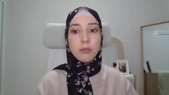A woman wearing a headscarf speaks via video call