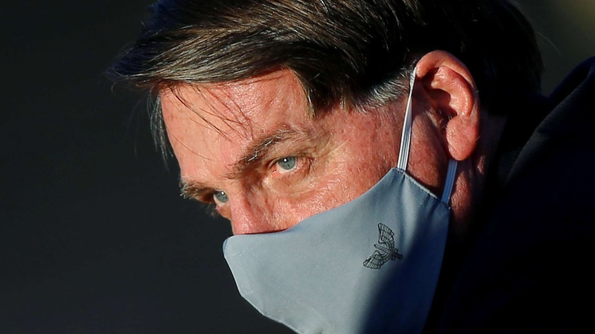 A close up shot of Jair Bolsonaro's face in a grey face mask