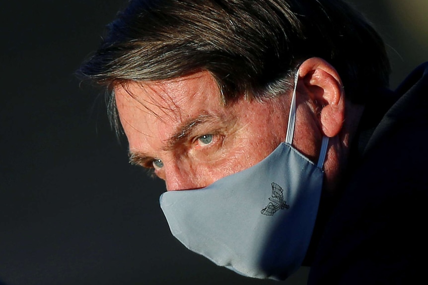 A close up shot of Jair Bolsonaro's face in a grey face mask