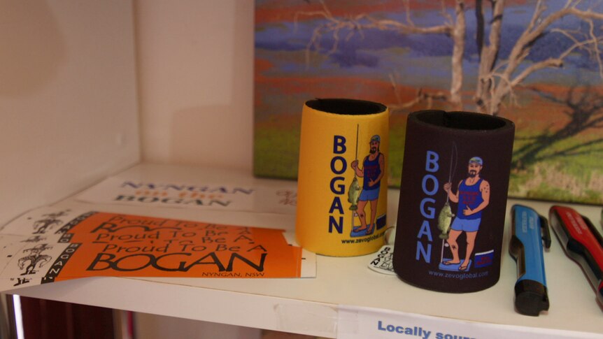 A set of stickers and stubbie holders lay on a bench that read 'Proud to be bogan' and 'Bogan