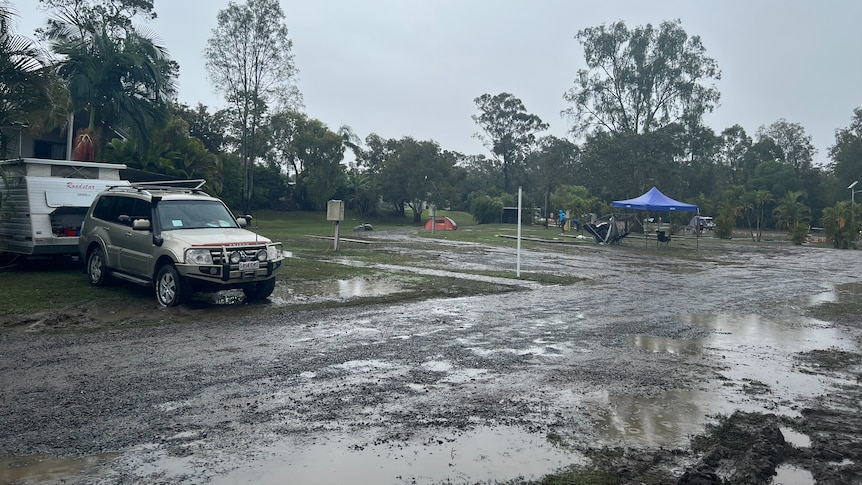 Muddy Big 4 Helensvale caravan park after heavy rainfall in the region. Van packed up, no tents in sight, just lots of puddles