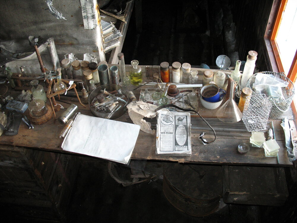 Bottles, notepads, equipment and other artefacts on a bench inside Scott's Terra Nova Hut.