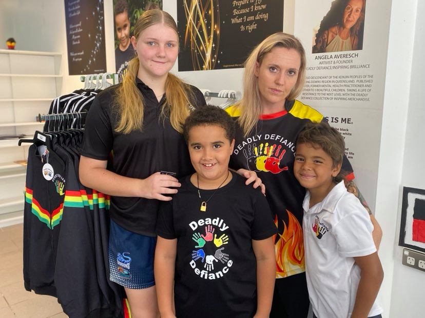 Angela smiling in a photograph with her three kids.
