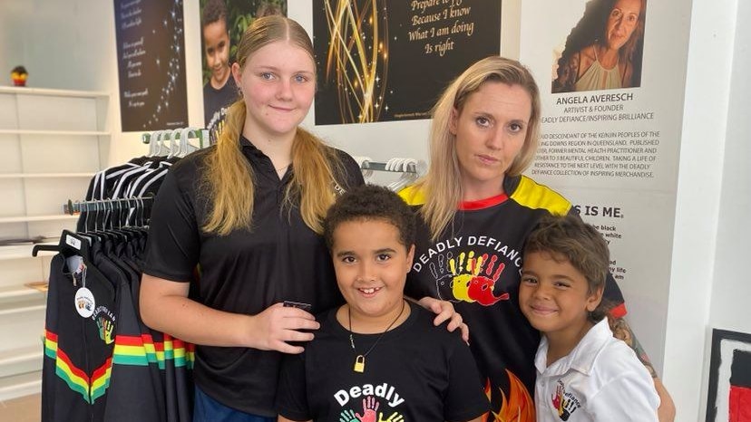 Angela smiling in a photograph with her three kids.