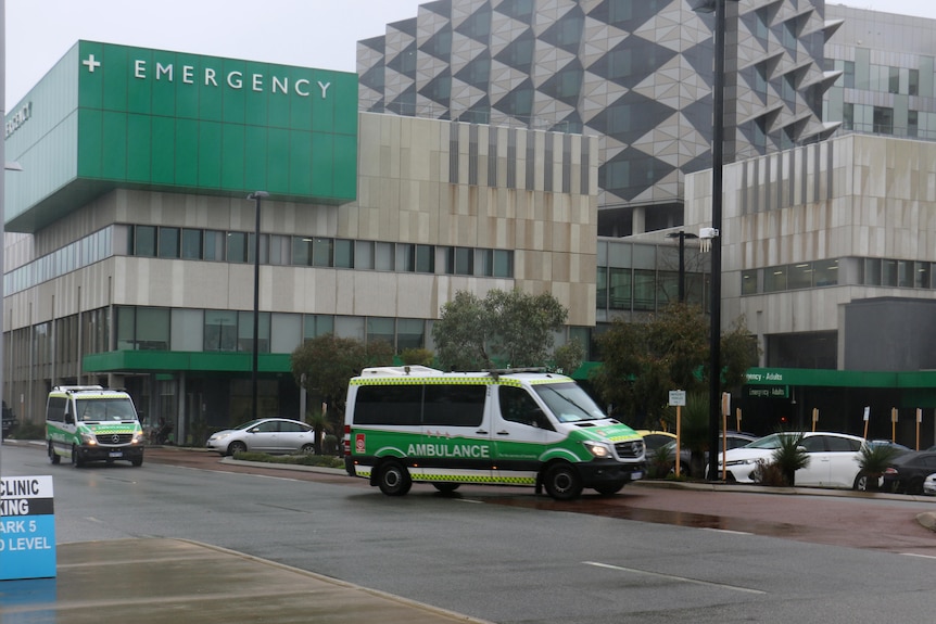 Two ambulances and a police car outside a hospital building.