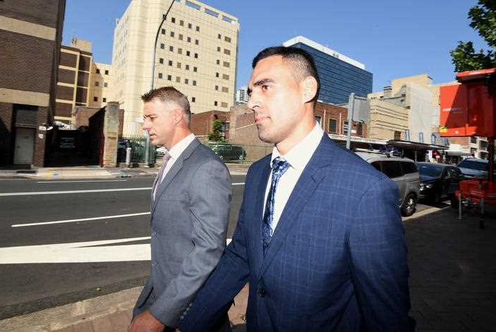 A man looking sullen walking down the street in a blue suit.